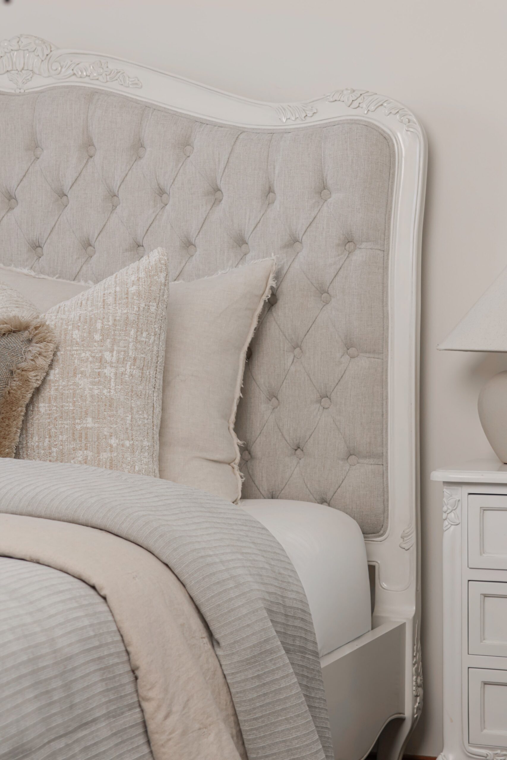 Alice French Provincial Bed with an antique white carved frame and neutral button-tufted upholstery