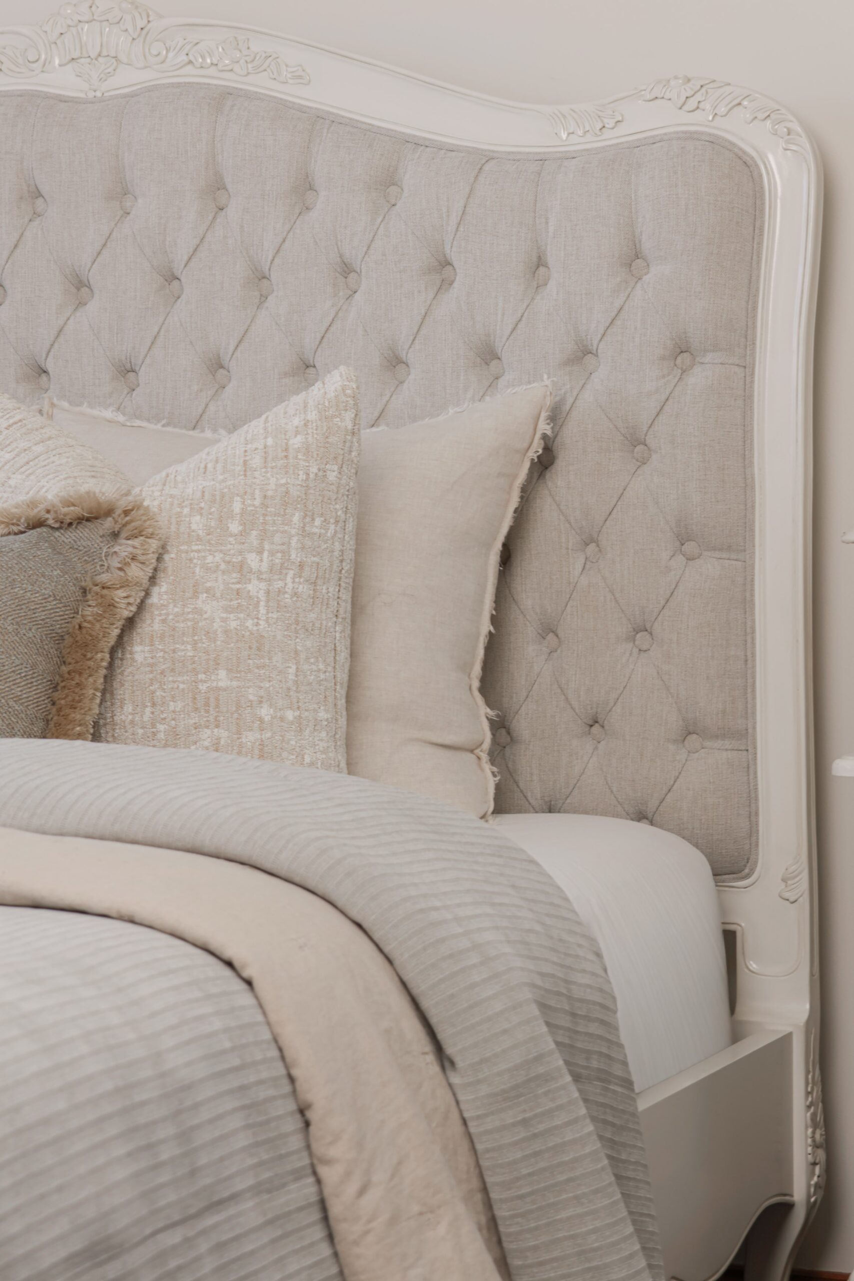 Alice French Provincial Bed with an antique white carved frame and neutral button-tufted upholstery