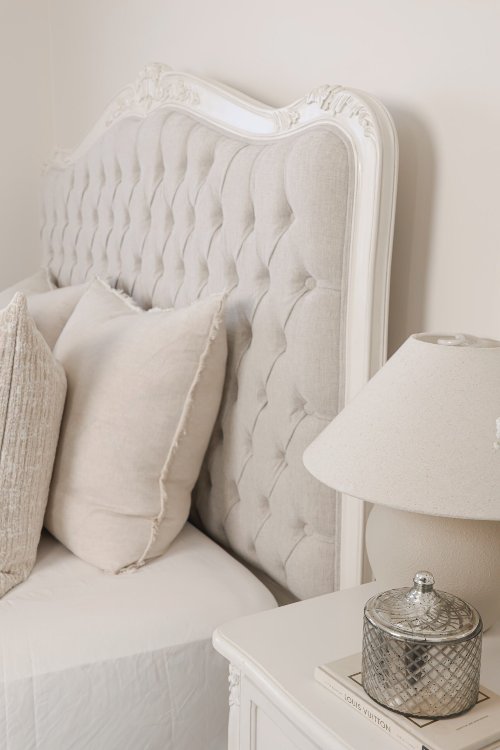Alice French Provincial Bed with an antique white carved frame and neutral button-tufted upholstery