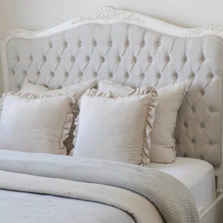 Alice French Provincial Bed with an antique white carved frame and neutral button-tufted upholstery