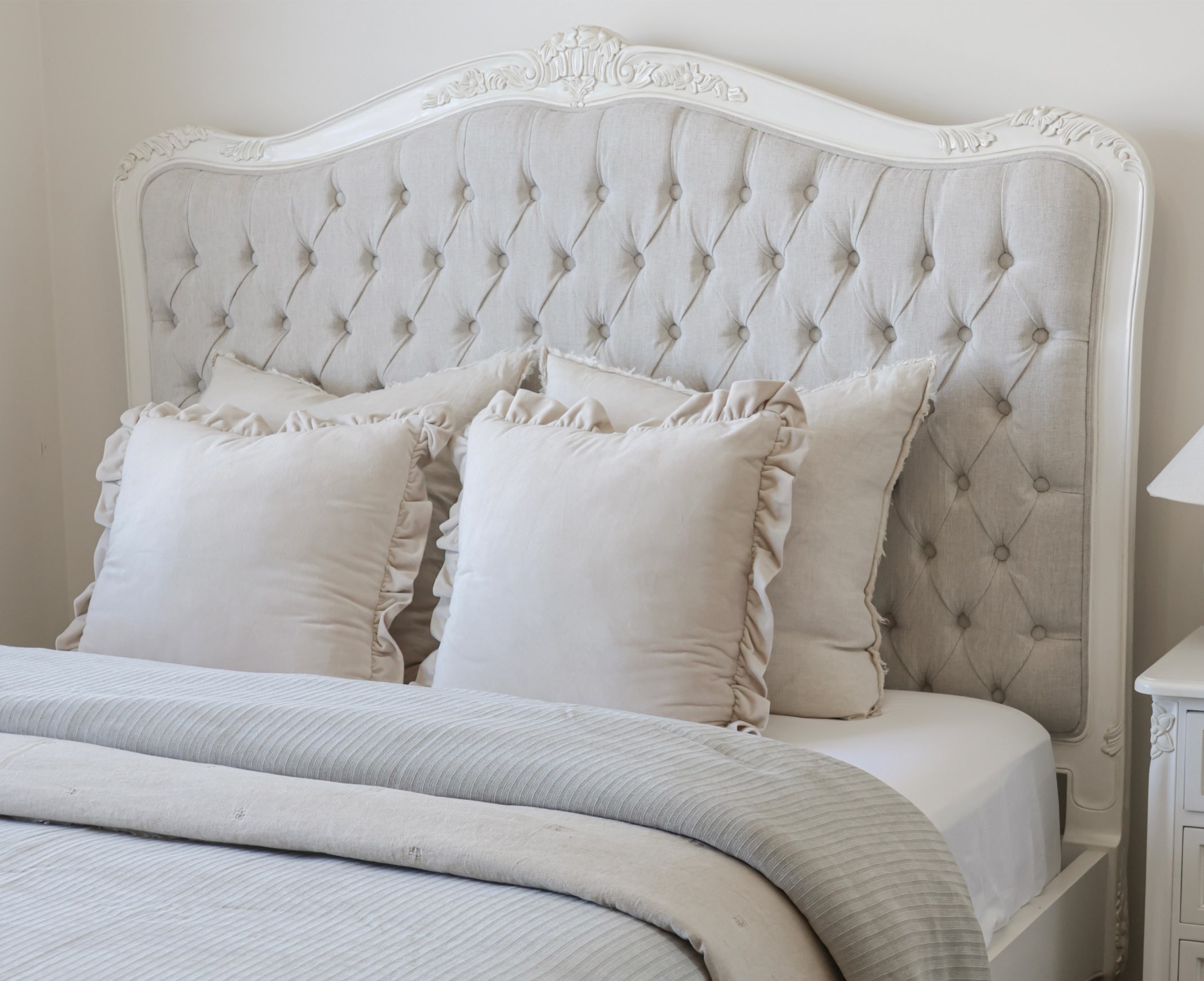 Alice French Provincial Bed with an antique white carved frame and neutral button-tufted upholstery
